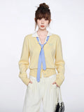 Woman wearing a pastel yellow knit cardigan with a white collar and blue striped tie