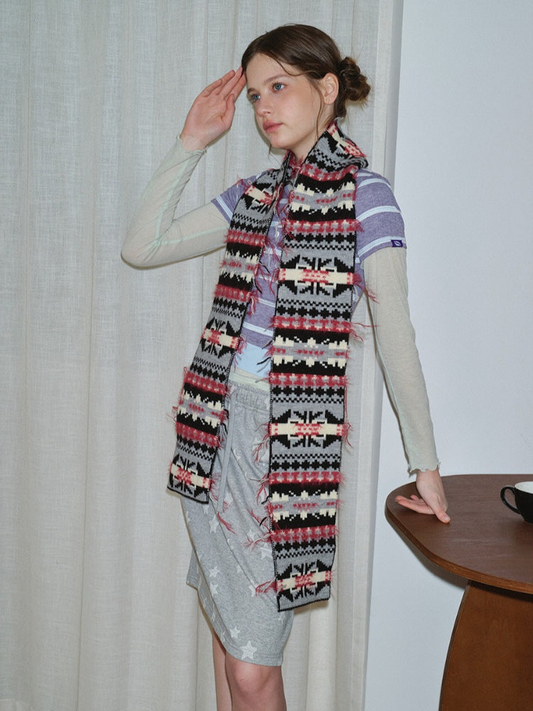Model styled with a knit scarf featuring a central geometric pattern and red fringe.