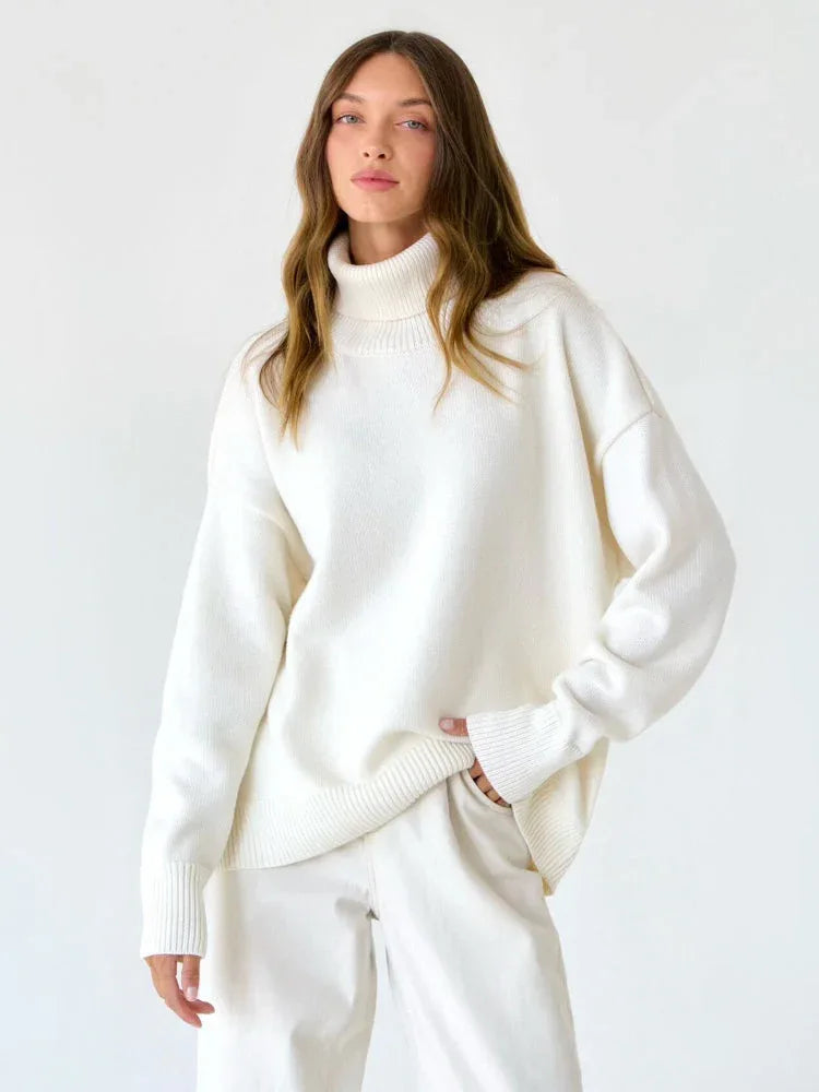 Woman wearing a white oversized turtleneck sweater and light wash wide-leg jeans.