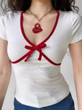 Front view of a fitted white top with red detailing and a bow