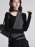 Woman posing with a black handbag, showcasing the black top with grey overlay
