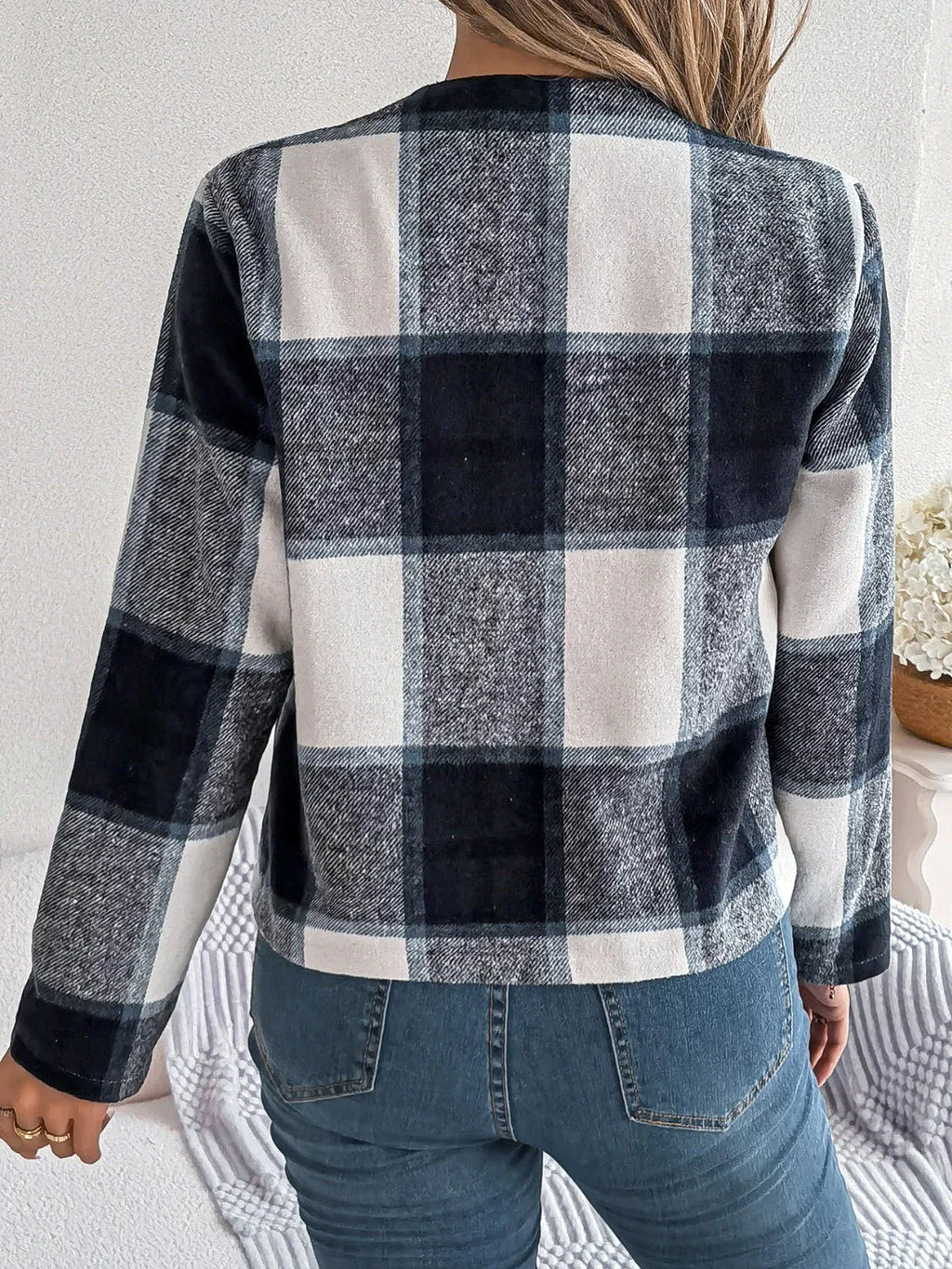Back view of a woman wearing a blue and white plaid jacket.
