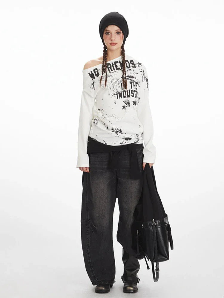 Woman wearing a white long-sleeve graphic print top with an off-the-shoulder design and black beanie.