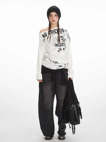 Woman wearing a white long-sleeve graphic print top with an off-the-shoulder design and black beanie.