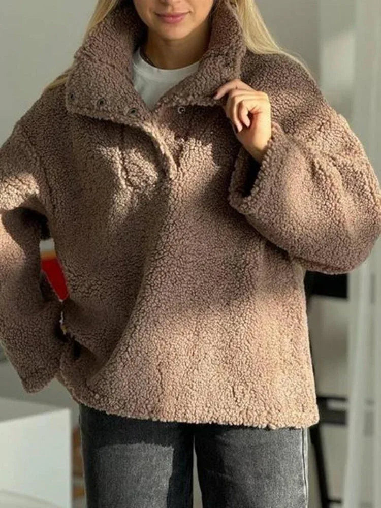 Woman adjusting the collar of her brown fleece top, showcasing the casual style.