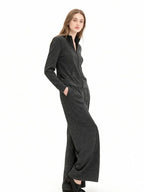 Woman wearing a charcoal grey knit loungewear set with a full zip jacket and wide leg pants, with hands in pockets.