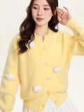 Woman posing in a yellow fuzzy knit cropped cardigan with cloud details.