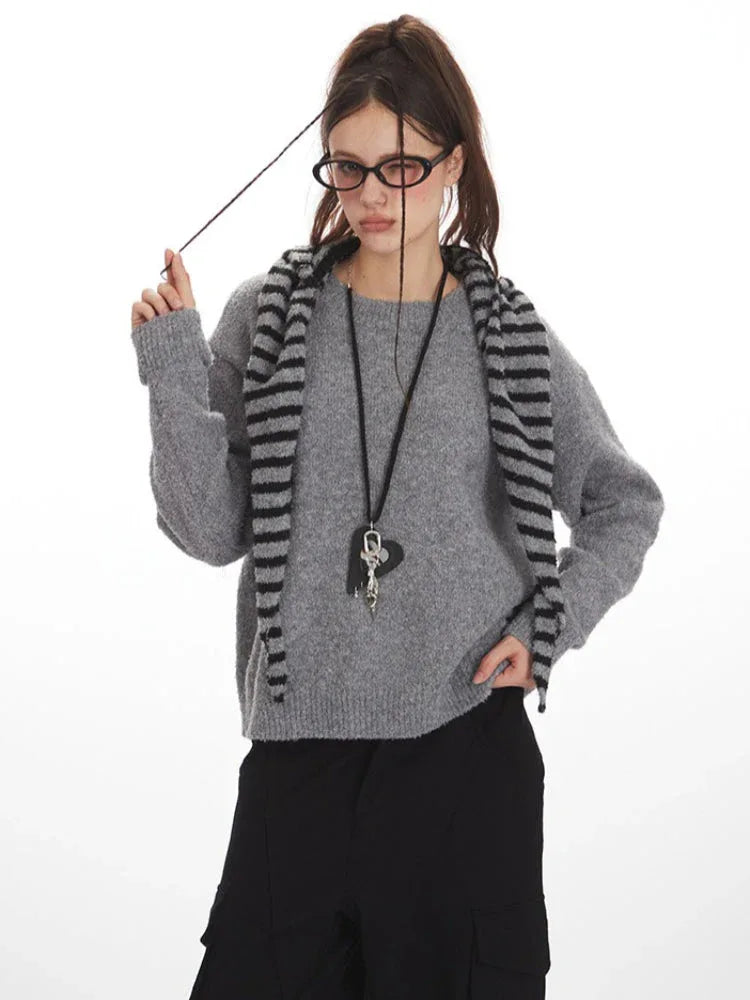 Woman adjusting her scarf while wearing a grey crew neck sweater and black cargo pants