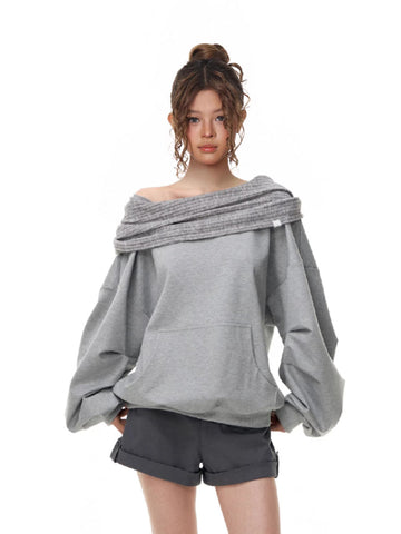 Woman wearing a grey off-the-shoulder sweatshirt with balloon sleeves and a ribbed cowl neck detail