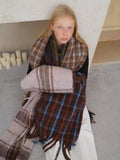 Woman wrapped in a plaid scarf with brown, blue, and pink tones