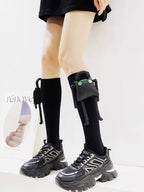 Black knee-high socks with a detachable plush toy embellishment on each leg, worn with black chunky sole sneakers.