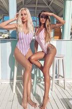 Two women wearing striped one-piece swimsuits