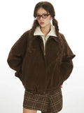 Woman posing in a brown corduroy bomber jacket with a plaid skirt.