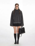 Woman wearing a grey fuzzy bomber jacket with plaid hem detail