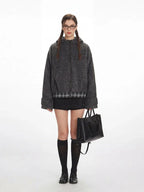Woman wearing a grey fuzzy bomber jacket with plaid hem detail