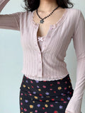 Front view of a pink cropped knit cardigan with matching buttons and delicate lace trim.