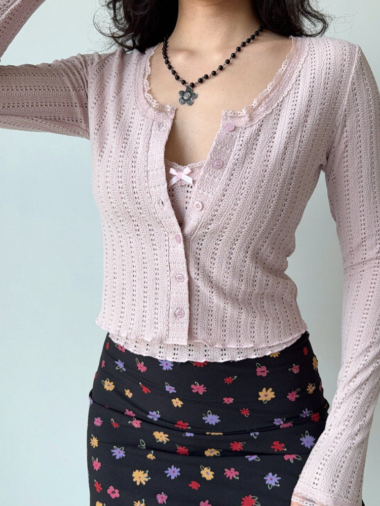 Front view of a pink cropped knit cardigan with matching buttons and delicate lace trim.