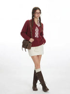 Woman wearing a burgundy V-neck sweater, white skirt, white knee-high socks, and brown buckle boots.