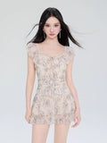 Woman wearing a cream-colored mini dress with a delicate butterfly print and ruffled neckline.