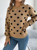 Front view of a woman in a tan polka dot sweater and blue jeans.