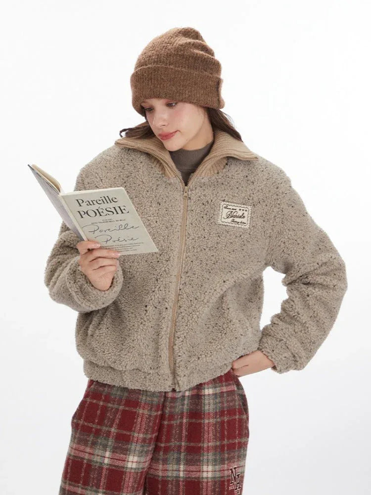 Model holding a book while wearing a tan fleece bomber jacket.