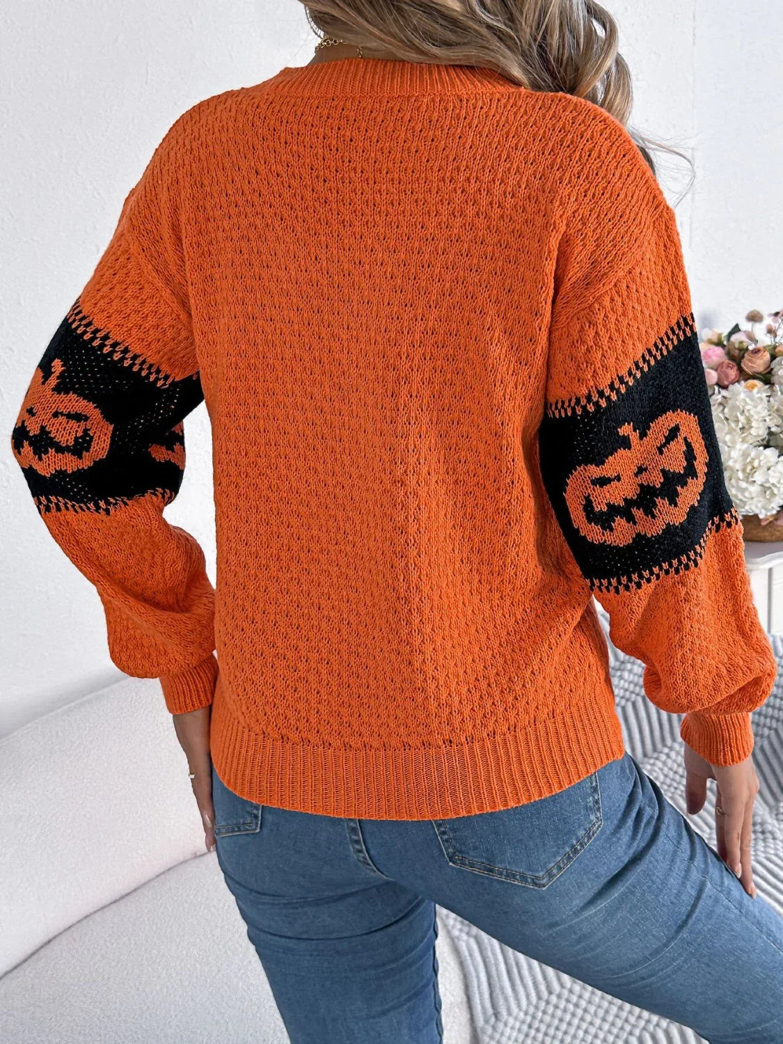 Back view of the orange knit sweater with lantern sleeves.