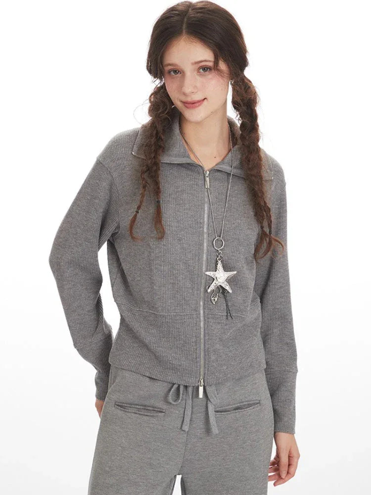 Woman wearing a grey ribbed knit loungewear set, with the jacket partially unzipped.