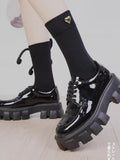Detail of a black sock featuring a twisted rope bow and heart charm.