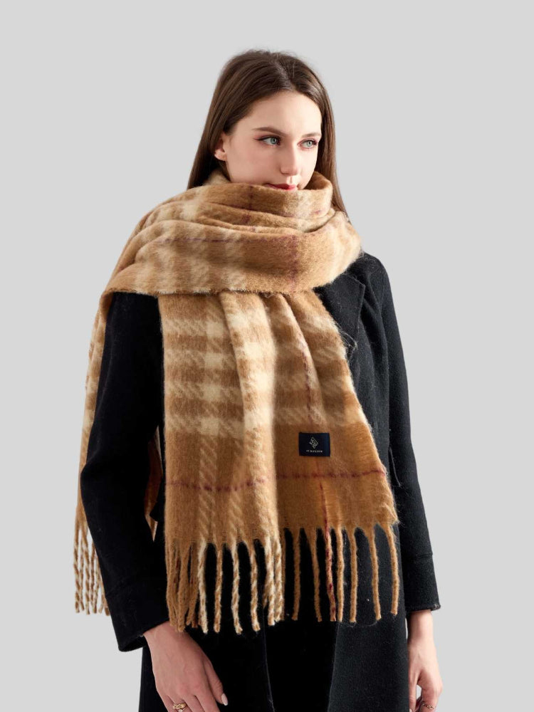 Woman wearing a tan and cream plaid scarf with fringe