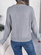 Back view of a woman wearing a grey long-sleeve knit sweater.