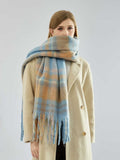 woman wrapping a blue and tan plaid scarf around her neck