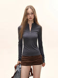 Model wearing a dark grey long-sleeve zip-up top with brown shorts.