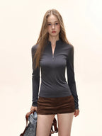 Model wearing a dark grey long-sleeve zip-up top with brown shorts.