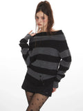 Close-up of a woman wearing a grey and black striped knit sweater styled off-the-shoulder, black shorts, black patterned tights, and black boots.