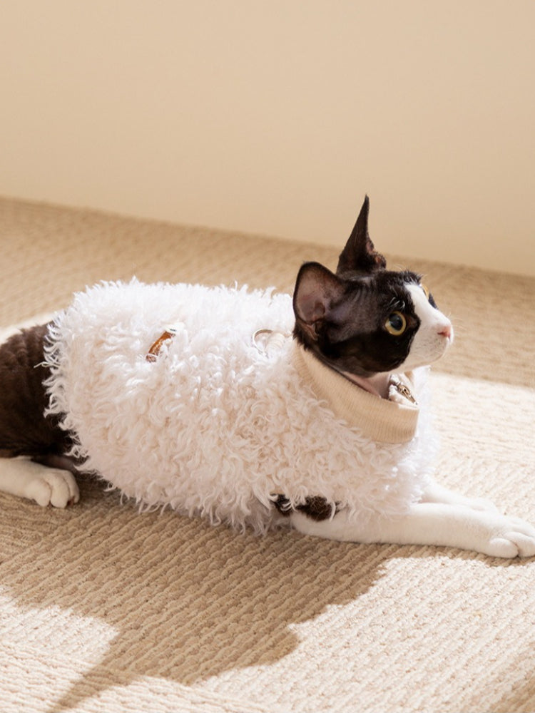 A black and white cat wearing a white faux fur coat resting.