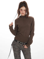 Close-up of a woman wearing a brown turtleneck sweater and patterned pants