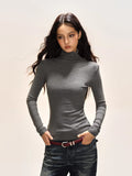 Model wearing a grey long-sleeve turtleneck top and dark wash jeans.