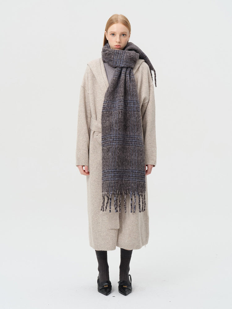 Woman wearing a grey and blue plaid wool blend scarf draped around her neck.