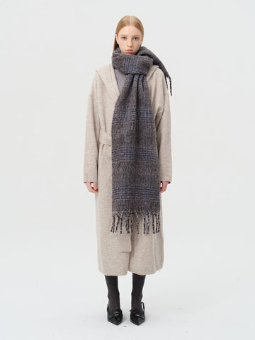 Woman wearing a grey and blue plaid wool blend scarf draped around her neck.