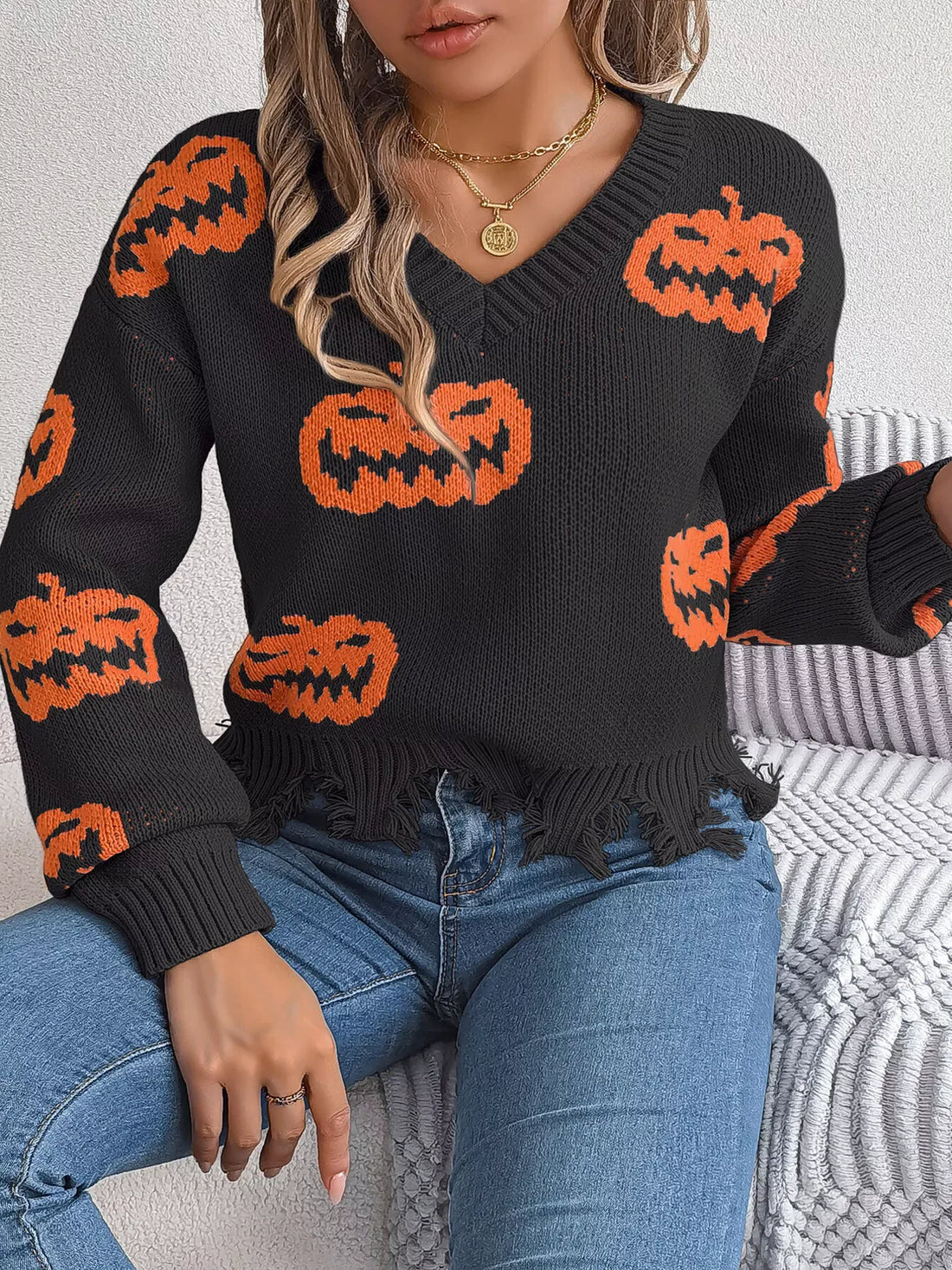 Woman in black knit sweater with orange pumpkins and distressed hem