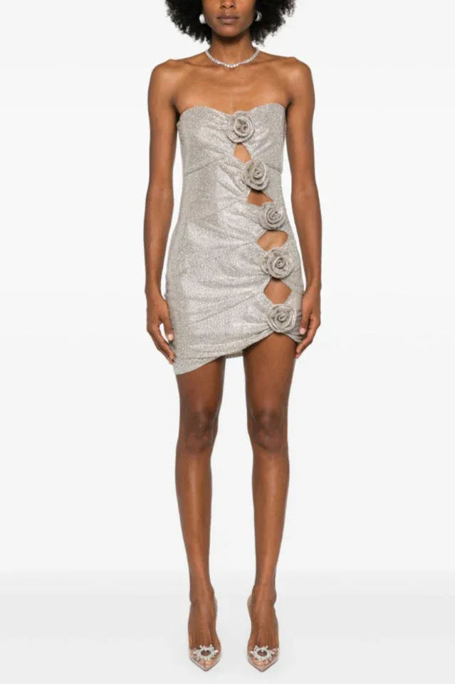 Woman in a silver sequined strapless dress with rose embellishments and an asymmetrical hemline.