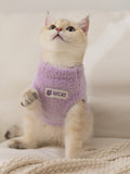 A light purple fluffy knit pet vest with a mock neck and a white logo patch on the front, worn by a light-colored cat.