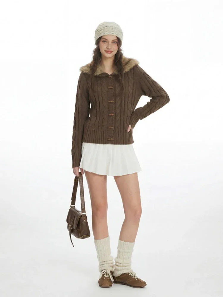 Woman wearing a brown cable knit cardigan with a faux fur collar and wooden buttons.