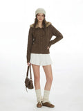 Woman wearing a brown cable knit cardigan with a faux fur collar and wooden buttons.