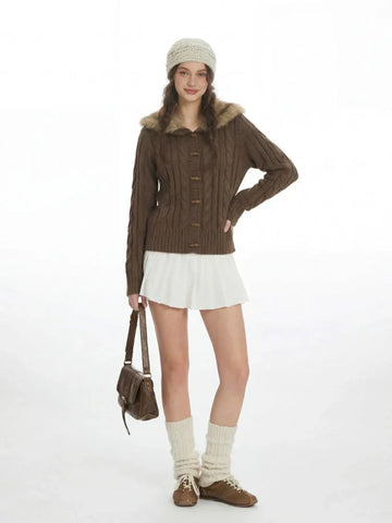 Woman wearing a brown cable knit cardigan with a faux fur collar and wooden buttons.