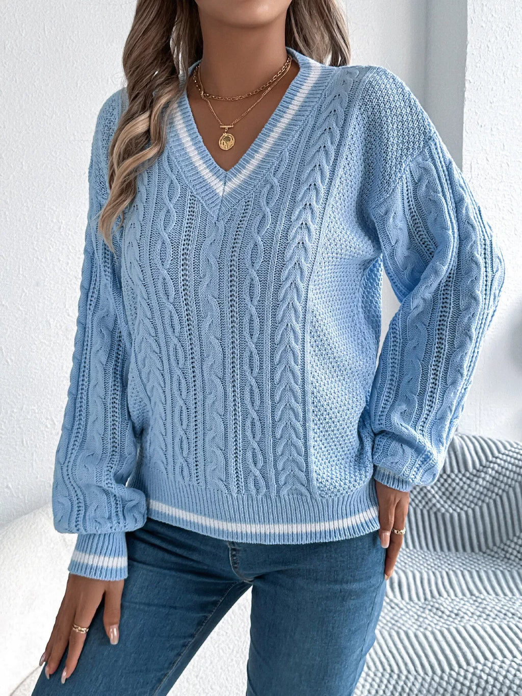 Close-up of the front of a light blue cable knit v-neck sweater