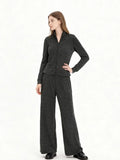 Woman wearing a charcoal grey knit loungewear set with a full zip jacket and wide leg pants, side view.