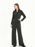 Woman wearing a charcoal grey knit loungewear set with a full zip jacket and wide leg pants, side view.