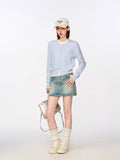 Model posing in a light blue knit cardigan with a white undershirt