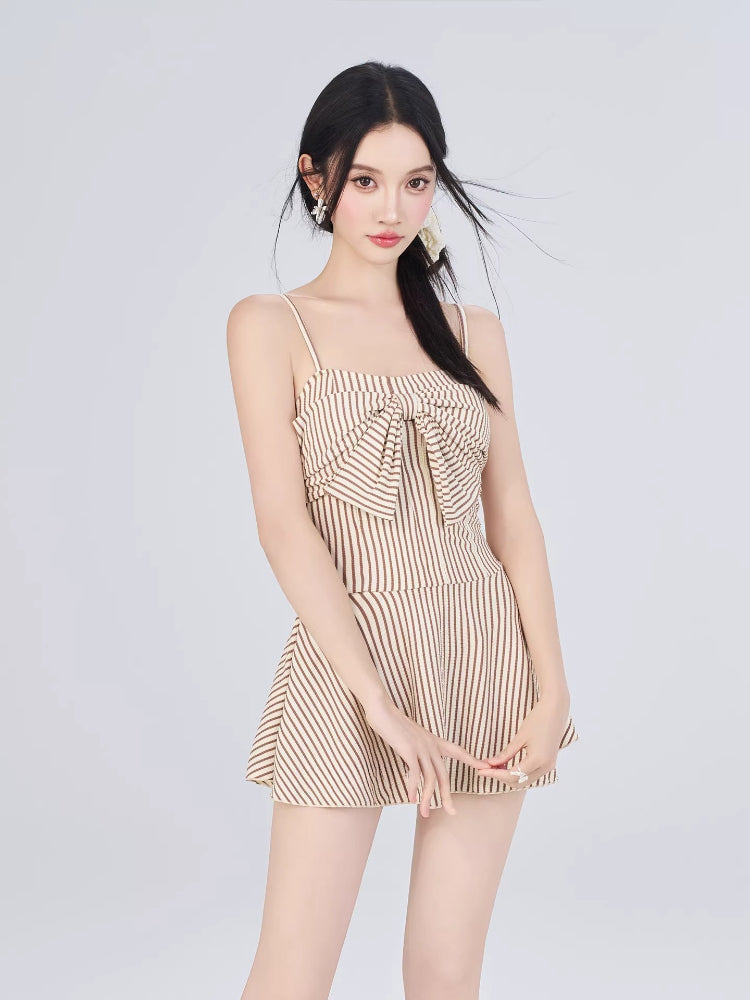 Woman in a striped fit and flare dress with a bow detail, front view.
